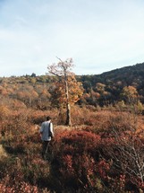 man walking up hill on a fall mountaintop 