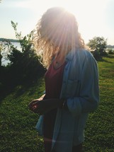 woman standing outdoors with a sunburst over her face 
