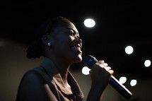 A woman on stage leading a worship service 