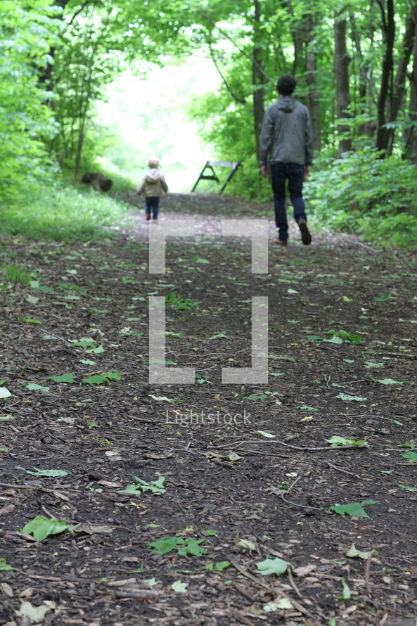 father and son walking on a path in the woods 