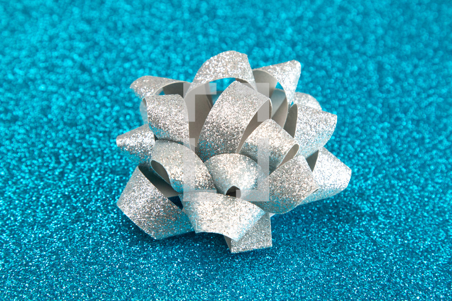 silver bow on blue glittery background 