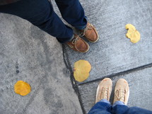 Fall leaves and shoes on a sidewalk 