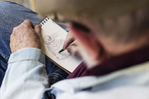 elderly man sketching a drawing on paper 