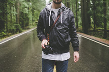 a man with a camera standing in the middle of a road 