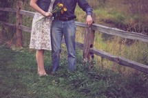 a couple standing by a fence outdoors in the country 