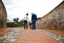 a family walking on a brick sidewalk holding hands 