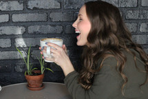 a woman sitting at a table drinking coffee 