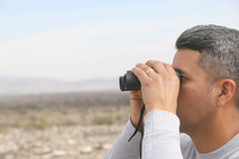 a man looking through binoculars 