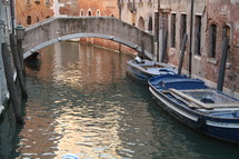 Bridge over moat with boats in the water.