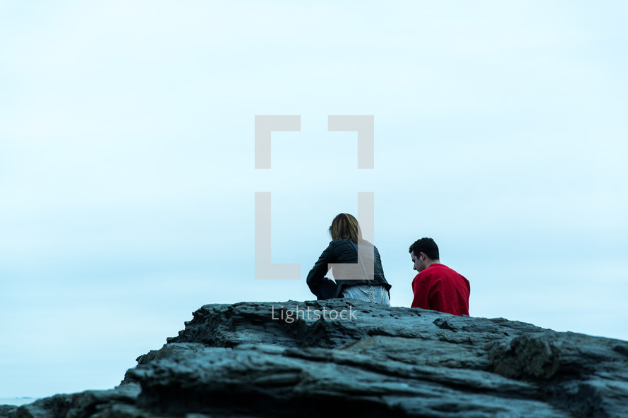 couple sitting on top of a rock 