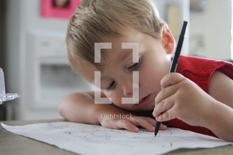 a toddler boy drawing on paper 