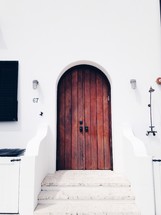 steps to an arched wood door 