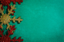 gold and red snowflake ornaments on a green background 
