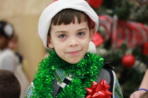 A little boy wrapped in Christmas tinsel.