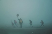 children crossing a crosswalk with a crossing guard on a foggy morning 