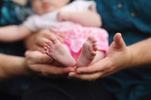 Parents holding baby girl's feet