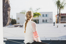 teen with a braided pony tail sitting outdoors 