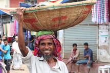 Bangladeshi man with a basket on his head in the market 