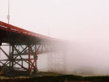 An orange bridge covered in fog.
