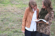 women standing outdoors reading a Bible 