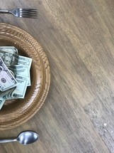 offering plate full of cash as a place setting 