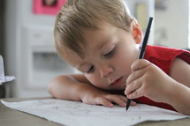 a toddler boy drawing on paper 