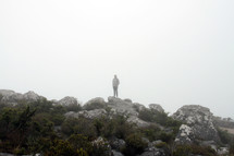 a man standing on rocks in the fog 