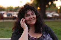 A smiling woman talking outside on a cell phone.