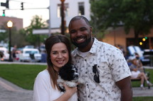 A smiling couple holding a puppy.