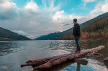 a man standing on a log in a lake 