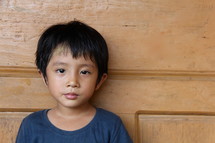 face of a boy child leaning against a door 