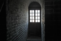Sunlight shining through a window into a dark brick room