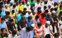 Muslim men kneel in prayer in a city mosque