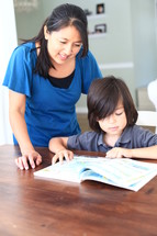Mother helping son read book