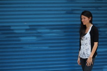 a young woman standing in front of a blue wall 