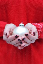cupped hands holding a Christmas ornament 