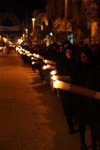 procession of people walking through the streets carrying candles 