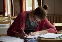 a woman writing in a notebook at a Bible study 