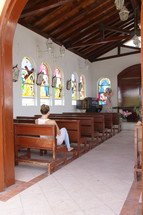 A woman sitting alone in a church sanctuary.