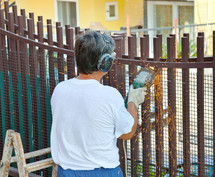 Worker cuts iron bars off a fence with grinder.