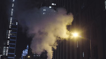 smoke between buildings in a city at night 