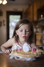 little girl blowing out birthday cake candles 