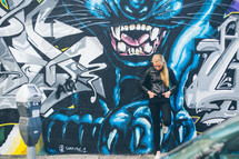 a woman standing next to a panther painted on an exterior wall 
