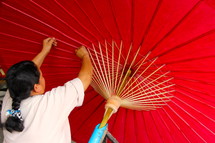 An Asian woman making a parasol / umbrella 