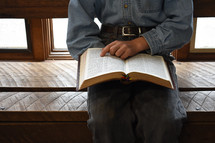 a boy sitting reading a Bible 