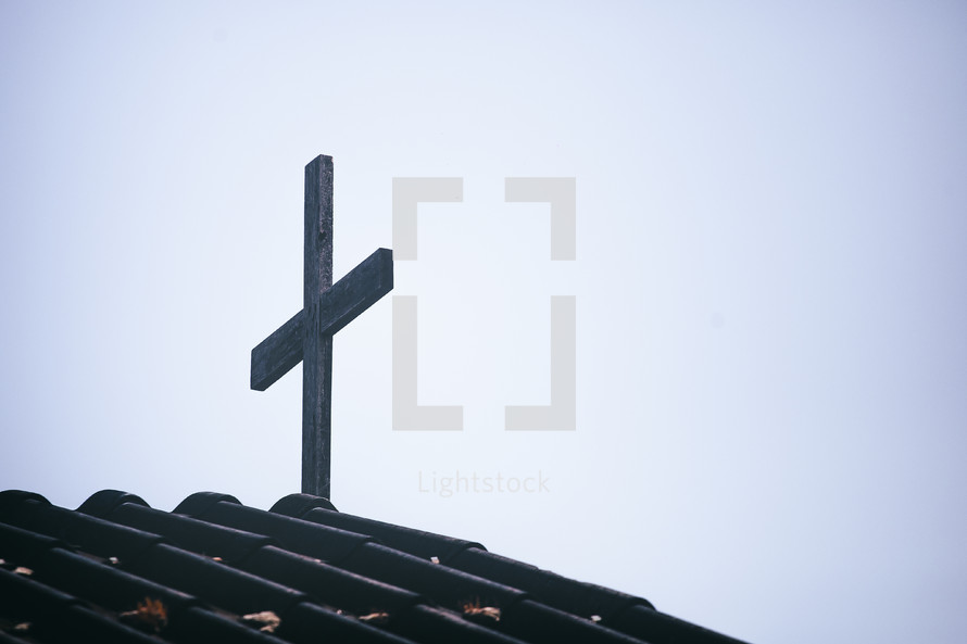 cross on a roof of a church against a blue sky 