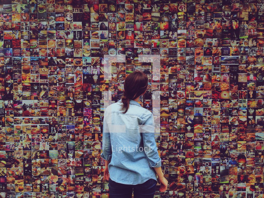 woman looking at a collage of photographs on a wall 