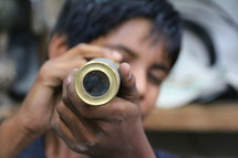 Young boy peers through an old brass telescope