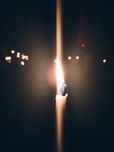 flame on a candle and distant bokeh lights 