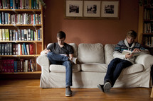men sitting on a couch in a library reading a Bible 